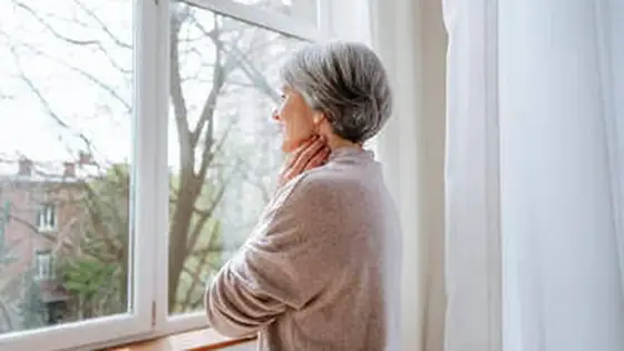 Mujer junto a una ventana con luz natural, en calma
