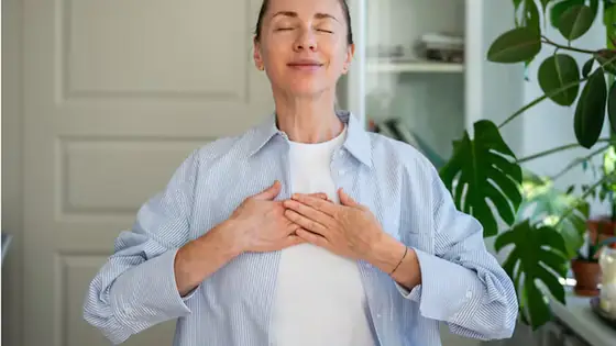 Mujer con las manos sobre el pecho y el abdomen, respirando con calma