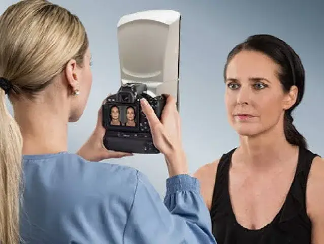 Profesional capturando imágenes 3D del rostro de una paciente con Vectra H2 en la consulta